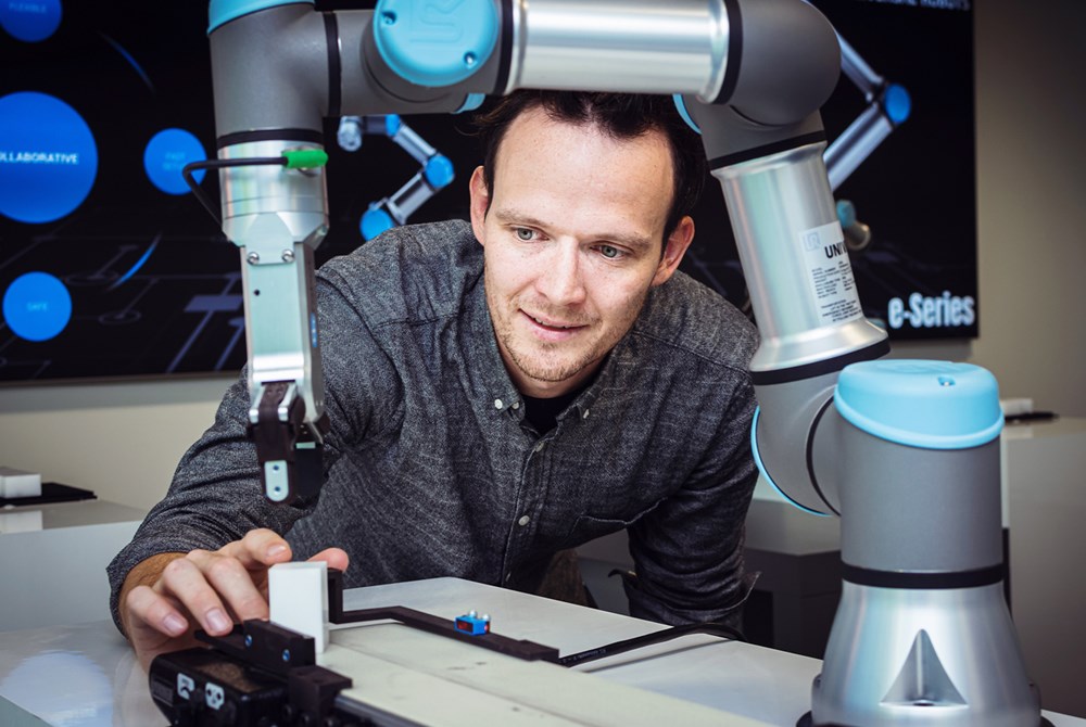 Ein Roboterprogrammierer programmiert den vor ihm platzierten Cobot von Universal Robots