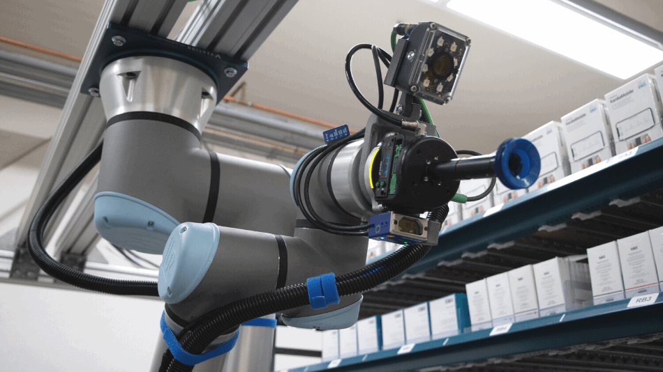 Ein Roboterarm hängt von der Decke und streckt einen Sauggreifer in die Kamera.