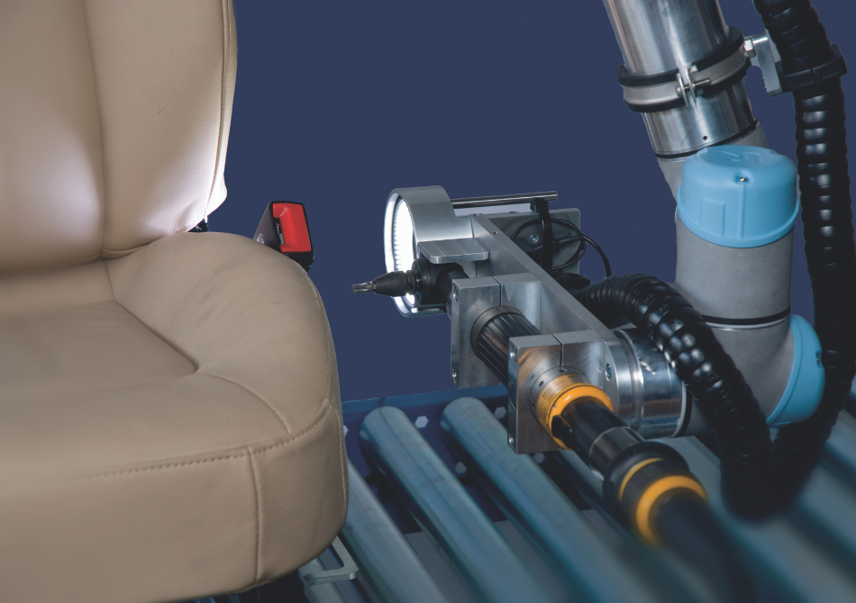 Ein Roboterarm ist mit einem Schrauber und einer Lampe ausgestattet. Er führt den Schrauber hin zu einem Autositz.