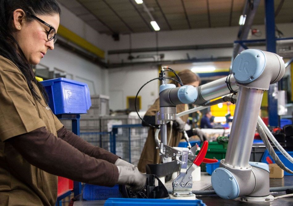 Eine Frau und ein kollaborierender Roboterarm arbeiten Seite an Seite.