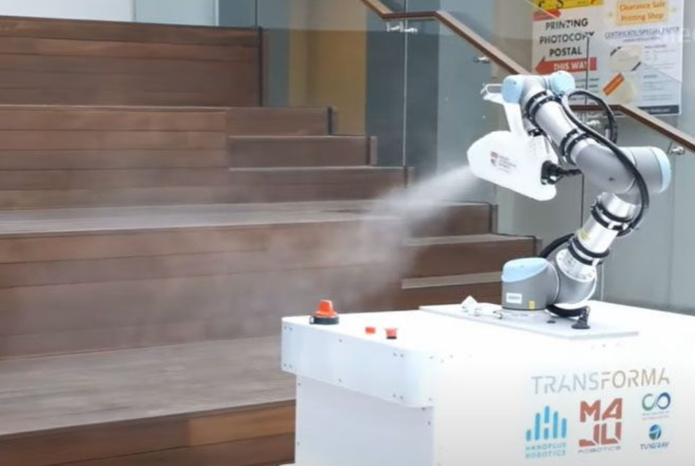 Ein Cobot von Universal Robots besprüht eine Treppe mit Desinfektionsspray. Der Roboter ist auf einer mobilen Plattform angebracht.