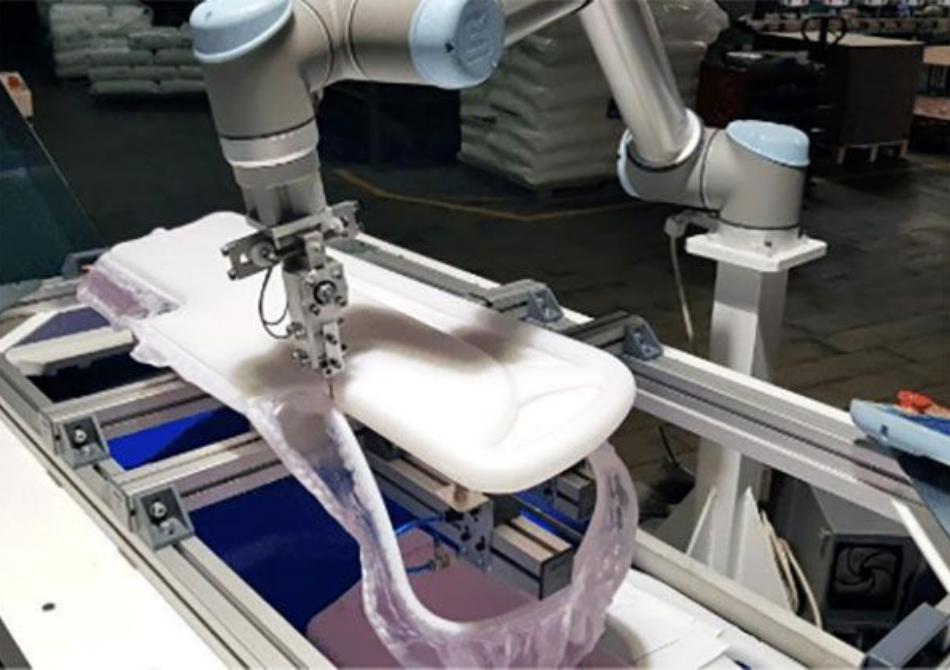 Ein Roboterarm schneidet ein blasgeformtes Teil für ein Krankenhausbett.