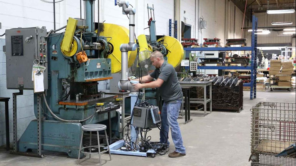 คนงานในโรงงานที่ Scott Fetzer Electrical ตั้งโปรแกรมแขนหุ่นยนต์ที่ถูกติดตั้งบนล้อเพื่อทำการผลิตแผ่นโลหะในอุตสาหกรรมโดยอัตโนมัติ