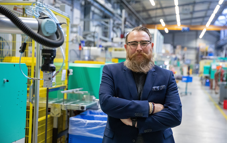 Der VEMA-Geschäftsführer Christian Veser präsentiert sich vor seinen Cobots.