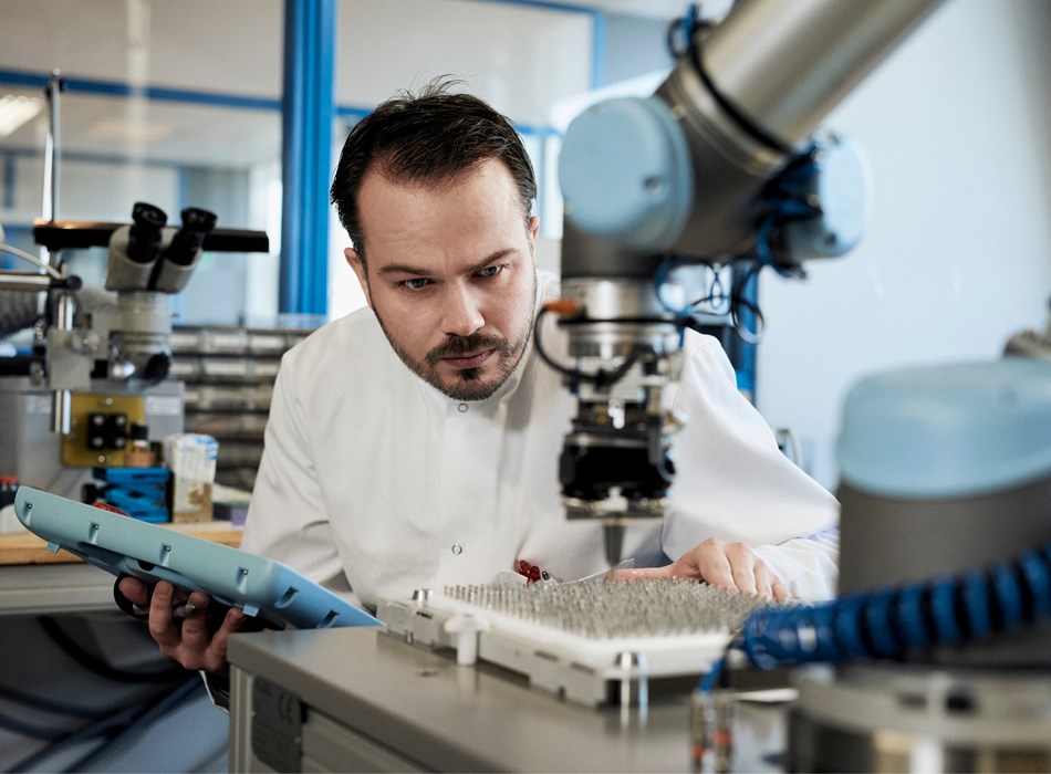 Ein Roboterprogrammierer programmiert den vor ihm platzierten Cobot haargenau.