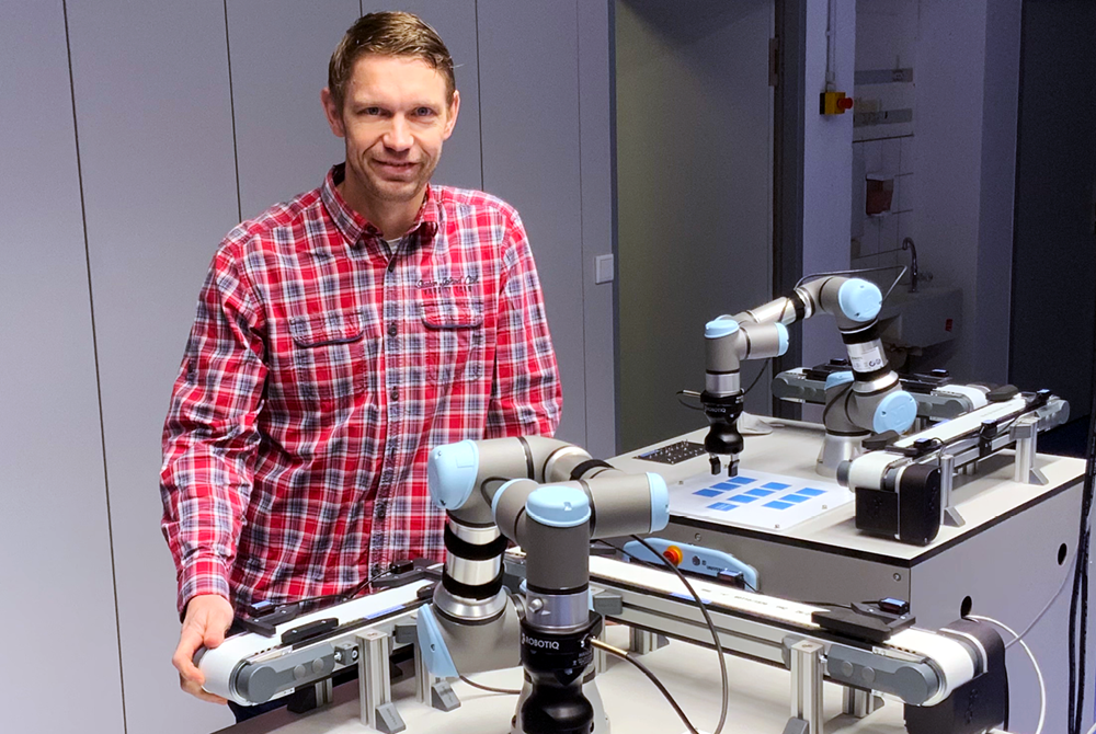 Der Berufsschullehrer Herr Schmidchen steht neben einem der Cobots. 