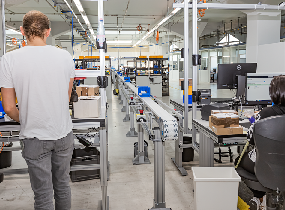 Zwei Mitarbeiter sind in der Fabrikhalle von rebuy zu sehen.