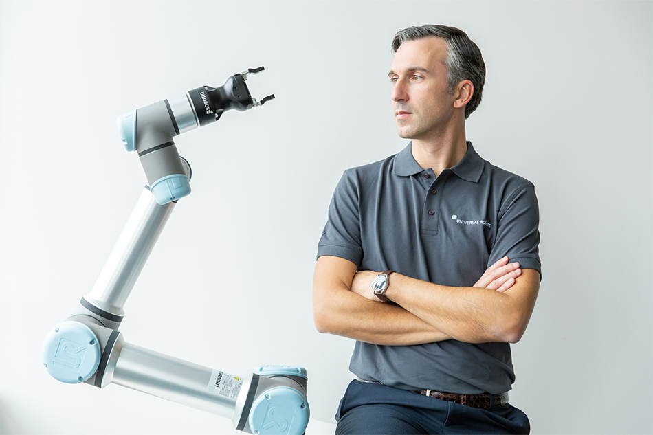 Hier sieht man Andrea Alboni, General Manager Western Europe bei Universal Robots neben einem Cobot von Universal Robots.