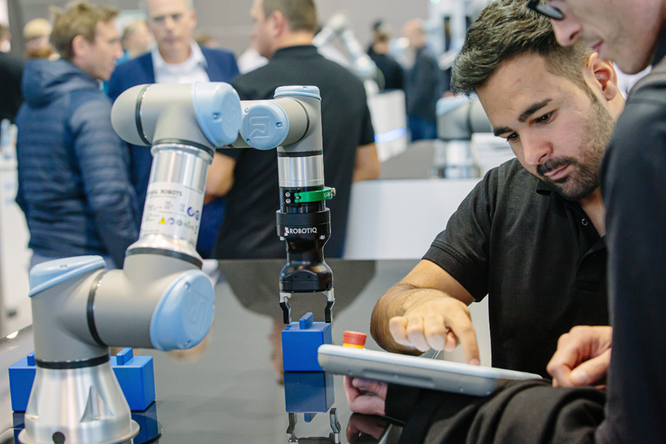 Hier zeigt ein Mitarbeiter von Universal Robots einem Kunden was vor. 