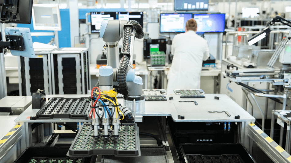 Ein Cobot greift mit einem Sauggreifer drei Leiterplatten gleichzeitig und platziert sie in einem Tray.