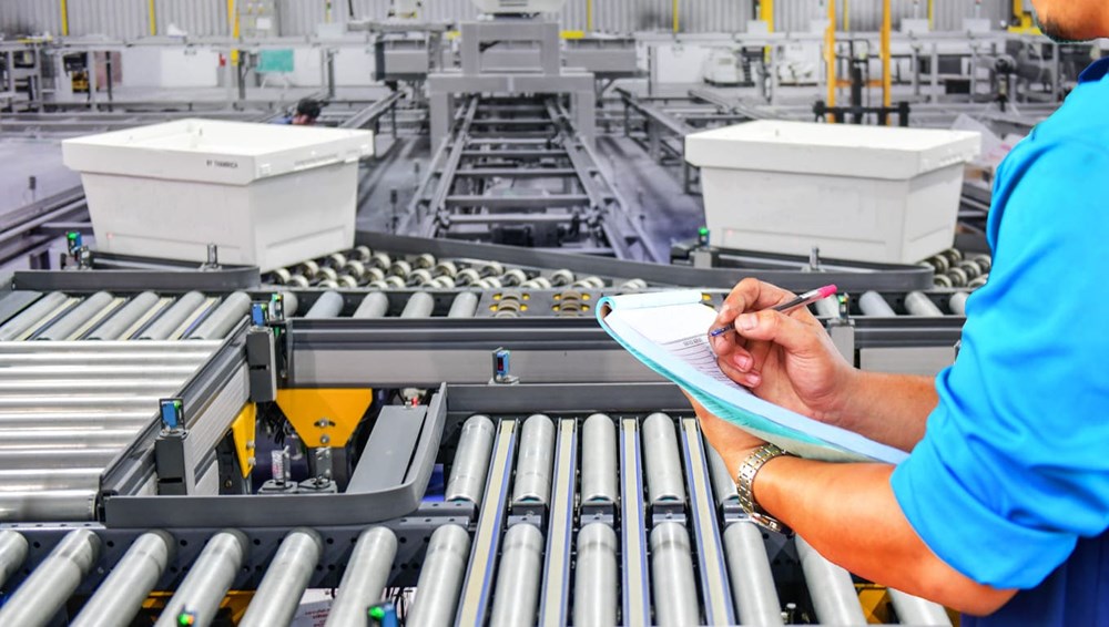 Técnico anotando medições em linha de produção com esteiras e caixas, representando o lead time na indústria