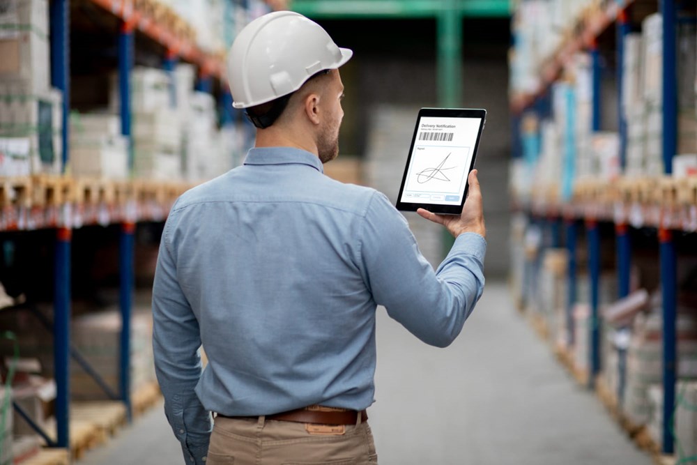 Supervisor em armazém usando tablet para registrar entrega e monitorar cycle time da operação logística